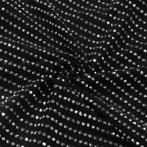 Close-up macro view of shimmering silver rhinestones on black stretch fabric dress detail