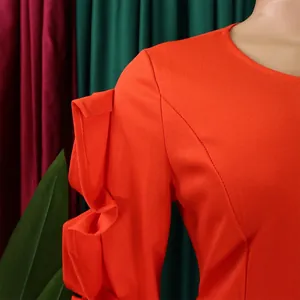 Close-up detail of ruffled sleeves and neckline on elegant orange long sleeve dress.