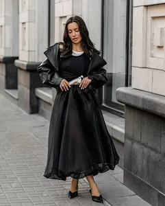 Modella che indossa una gonna lunga a ruota in mesh nero trasparente in un contesto urbano.