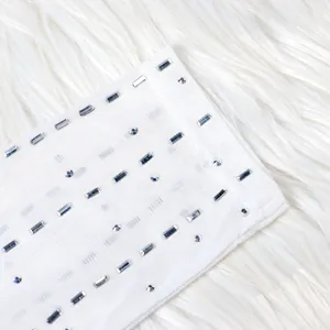 Close-up detail of shimmering silver rhinestones on a white mesh evening dress sleeve