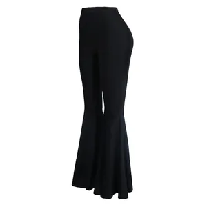 Detalle de pantalones acampanados negros de cintura alta con dobladillo de volantes.