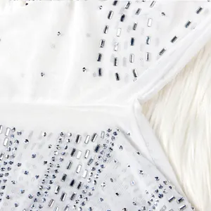Close-up view of elegant silver rhinestones on white mesh fabric for a nightclub dress.