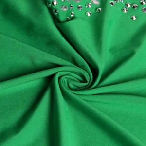 Macro view of sparkly silver rhinestones on vibrant green dress fabric texture detail
