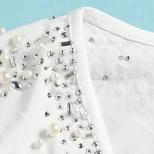 Dettaglio di un body bianco trasparente con eleganti decorazioni di perle e strass