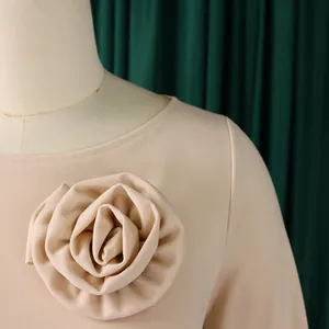Gros plan d'une robe beige élégante avec un détail de fleur en tissu 3D exquis.