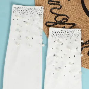 Dettaglio della tuta bianca trasparente decorata con perle e strass scintillanti