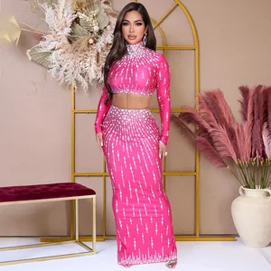 Elegante roze tweedelige feestset met strass, crop top met lange mouwen en maxirok.