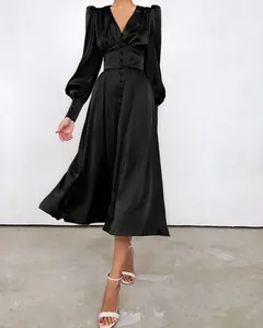 Elegante zwarte satijnen theejurk met lantaarnmouwen en knoopdetails in de taille.