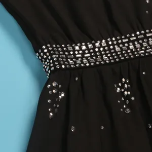 Primo piano di una tuta nera senza maniche con decorazioni in strass scintillanti.