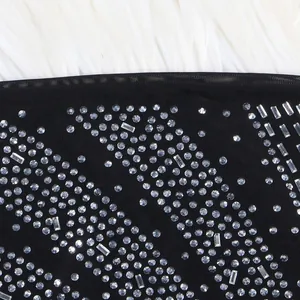 Detailed view of shimmering rhinestones on black mesh fabric of an evening dress