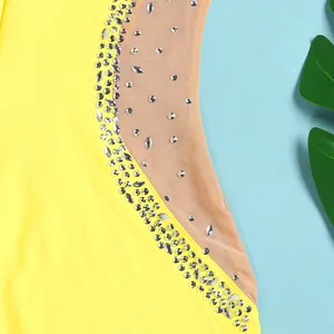 Close-up of sparkling rhinestone details on sheer mesh panel of yellow dress.