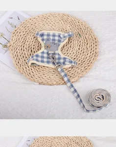 Close-up detail of blue plaid cat harness with cute cat embroidery and metal clip.