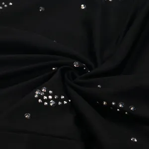 Dettaglio macro del tessuto della tuta nera con strass argentati scintillanti.