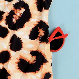 Close-up detail of leopard print dress fabric paired with red cat-eye sunglasses