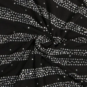Detailed macro view of shimmering silver rhinestones on black evening dress fabric