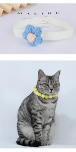 Detailed view of hand-knitted pet collar featuring a blue crochet flower and pom-poms.