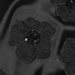 Vista macro di ricami floreali con paillettes nere su elegante tessuto di raso nero