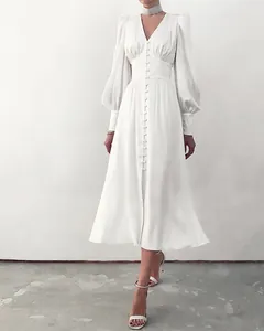 Detail van de elegante witte satijnen jurk met lantaarnmouwen en knoopsluiting voor