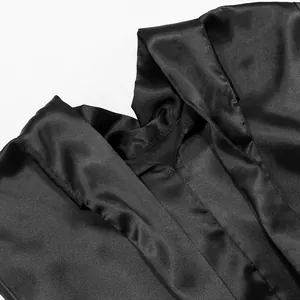 Dettaglio ravvicinato che mostra il liscio tessuto di raso nero e lo scollo di questo abito elegante