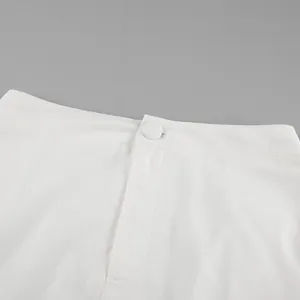 Close-up of the waistband and matching button detail on a white cotton linen skirt