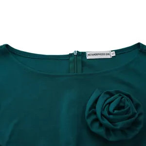 Gros plan d'une robe vert foncé à col rond avec rose en tissu détaillée