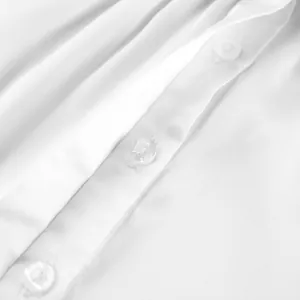 Primer plano detallado que muestra la textura suave y los botones de una camisa blanca