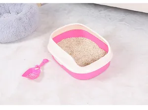 Μεγάλη ημίκλειστη ροζ αμμοδόχος γάτας με ασορτί φτυαράκι πάνω σε ένα μαλακό χαλί