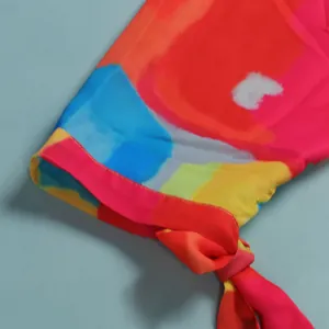 Close-up detail of a colorful abstract print dress sleeve with knot tie decoration