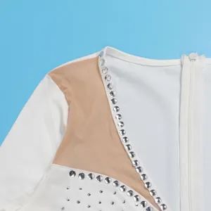 Dettaglio di una tuta in rete bianca con decorazioni di strass scintillanti e cerniera lampo.