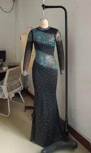 Detalle de un vestido de noche negro con pedrería brillante y mangas de malla fina.