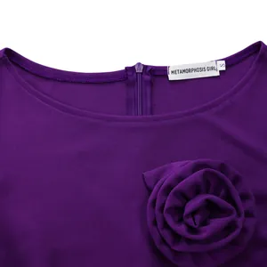 Détail d'une robe violette avec encolure ronde et grande décoration de rose en 3D.