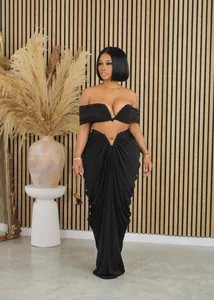 Detailed view of sexy black off-shoulder crop top and draped pleated floor-length skirt