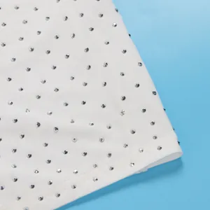 Dettaglio macro di tessuto bianco per tuta mesh con strass scintillanti applicati