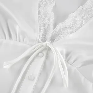 Close-up of white satin top with floral lace neckline and front bow tie detail