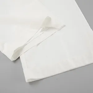 Zoom sur l'ourlet d'un pantalon large en coton et lin blanc avec texture respirante.