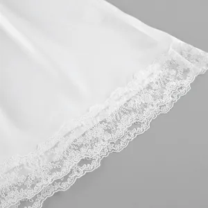 Detailed close-up of exquisite white floral lace hem on a luxurious satin dress