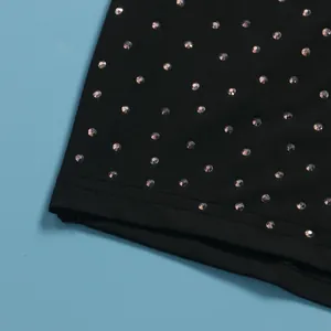 Vista macro dei dettagli in strass scintillanti sul tessuto elastico nero della tuta intera