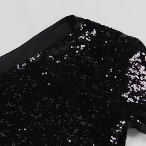 Κοντινό πλάνο με αστραφτερές μαύρες πούλιες σε ένα μακρυμάνικο φόρεμα για πάρτι.