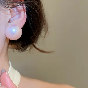 Close-up detail of a large pink semi-circular pearl stud earring with iridescent luster