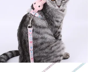 Close-up of a pink H-shaped cat harness with a cute plush rabbit on a tabby cat
