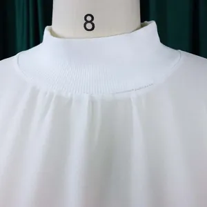 Close-up of white chiffon dress mock neck with pleated details and ribbed collar