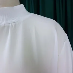 Detailed macro view of white chiffon dress featuring a mock neck ribbed collar design