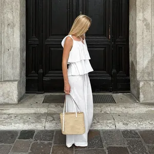 Femme élégante portant un ensemble deux pièces en lin blanc avec haut à volants et pantalon