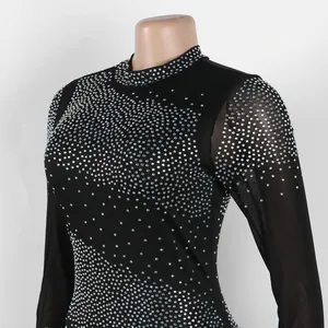 Detalle de vestido negro ajustado con pedrería plateada y mangas de malla transparente.