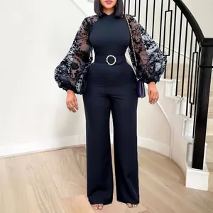 Close-up of black jumpsuit with mesh floral lantern sleeves and gold buckle belt.