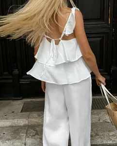 Vue arrière d'un élégant ensemble en lin blanc avec haut à volants et pantalon large pour femme