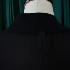 Detail view of the ribbed high-neck collar and brand label on a black chiffon dress.