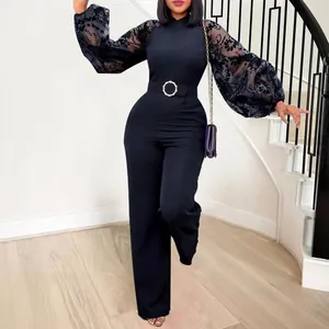 Detailed view of black jumpsuit featuring floral mesh sleeves and a buckled belt