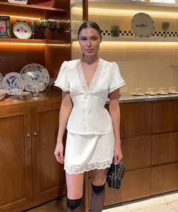 White satin two-piece set with lace trim shown on a model in a luxury kitchen setting
