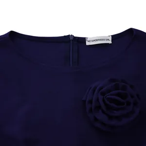 Détail d'une élégante robe bleu marine à col rond ornée d'une fleur en tissu